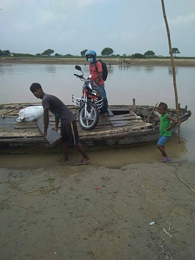 young men transporting motorbike by boat