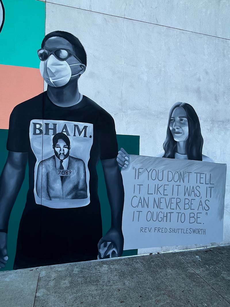 Mural depicting current day protesters against racial violence. One holds a sign saying "If you don't tell it like it was, it can never be as it ought to be. - Rev. Fred Shuttlesworth"